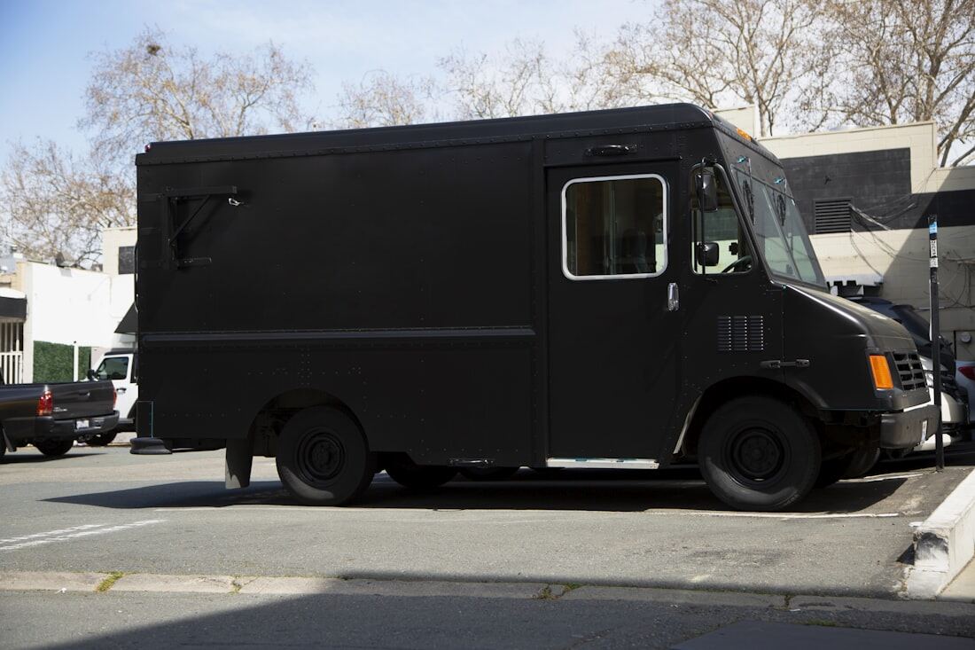 A dark commercial step van parked at the curb.